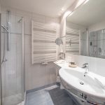 Ein Badezimmer mit einer Dusche einem Waschbecken und einem Spiegel.