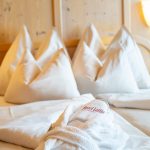 Ein Doppelbett mit Kissen, Bettdecke und einem Bademantel.