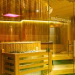 Latini_Entspannen_in_der_Sauna_2 A sauna with a glass front with a warm yellow light.
