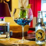 Latini_Gintime_1 Two bottles and a glass with a blue liquid.