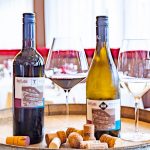 Latini_Weingenuss_2 Two bottles, each with a glass next to it.