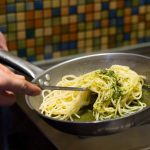 PapaRudolfo_PastaMachen_1 A person holding a pan with noodles in it.