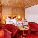 Zwei Sessel mit einem Tisch und einem Doppelbett dahinter.