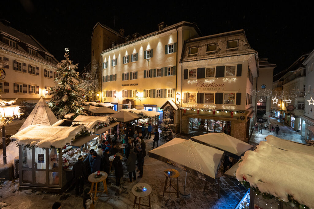 The Zeller Sternenadvent Market on Stadtplatz in Zell am See in the evening, with snow-covered huts and Christmas lights